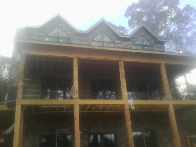 Dormers and porch framing on a large log home under construction — Roof Coating work by our crew in Braddyville