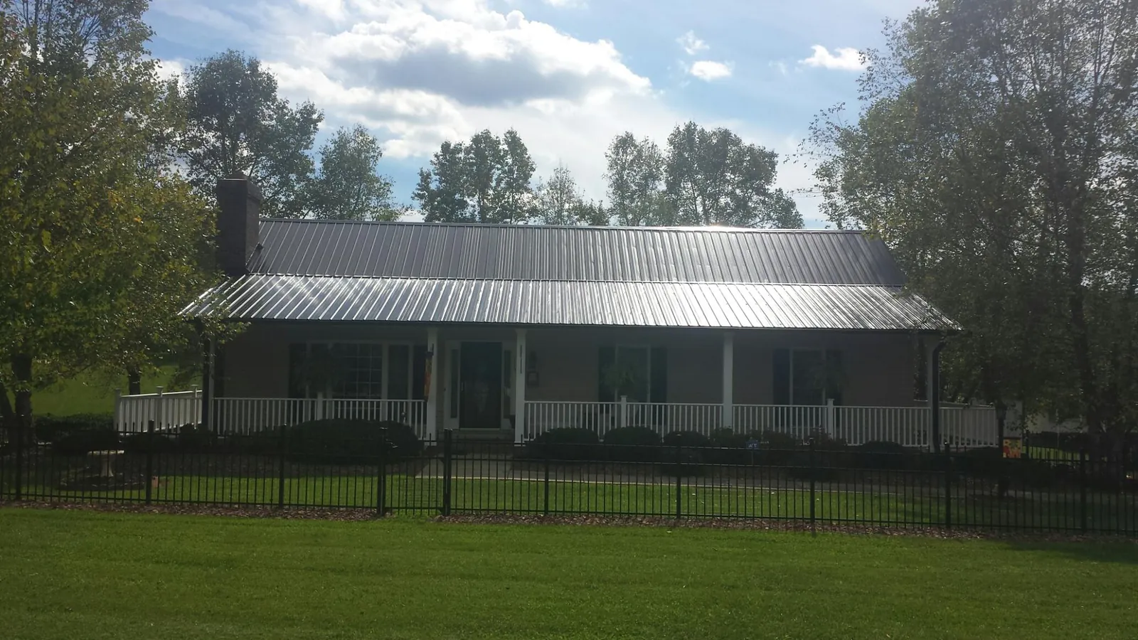Gray metal roof on a brick ranch with a full width front porch — Gutter Guard Installation work by our crew in Braddyville