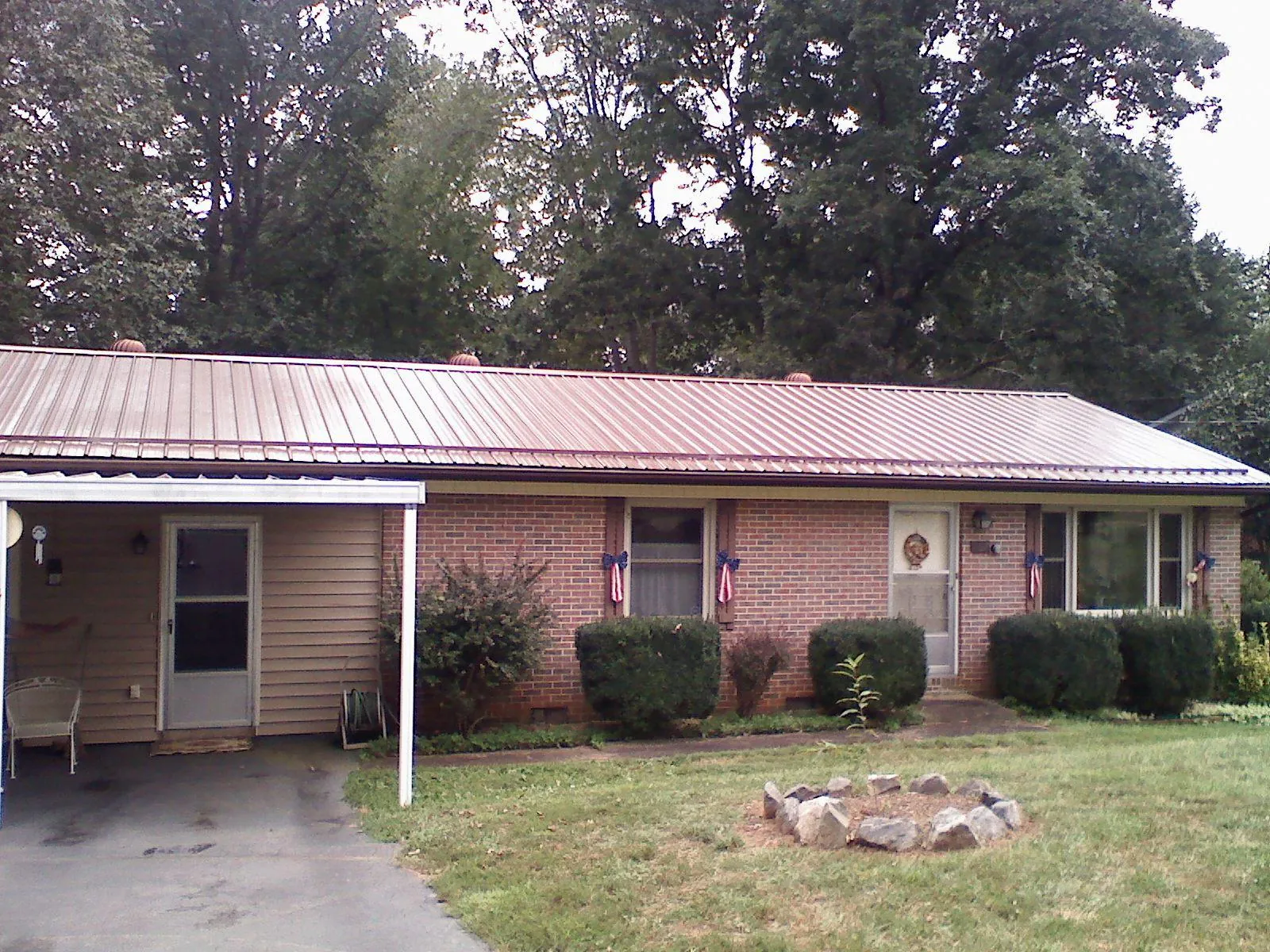 Bronze metal roof and carport on a brick ranch home — Roof Repair work by our crew in Braddyville