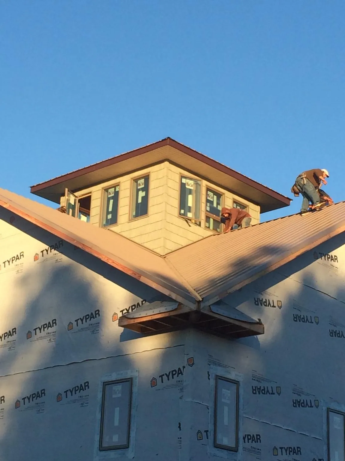 Roofers working around a rooftop cupola on a new metal roof at sunset — Roof Waterproofing in Braddyville by Roofing Brothers
